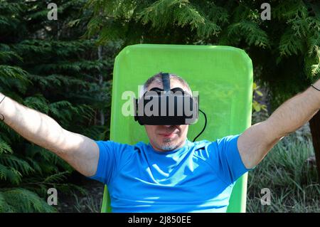 Happy man using a virtual reality headset enjoys the game and experiences a computer simulation of the virtual world. Stock Photo