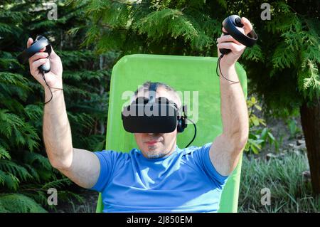 Happy man using a virtual reality headset and experiences a computer simulation of the virtual world and metaverse Stock Photo