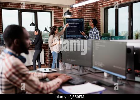 Security system developers analyzing application coding method in order to optimize data processing rate. Mixed race programmers team using machine learning to decypher encrypted stolen files. Stock Photo