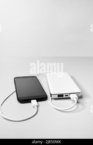 Smartphone is connected with a usb cable and is charged from the power bank battery Stock Photo