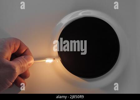 Top view of a sets fire to gas stove that has no gas with a match.No gas in the gas burner of the home kitchen stove due to the crisis and natural gas Stock Photo