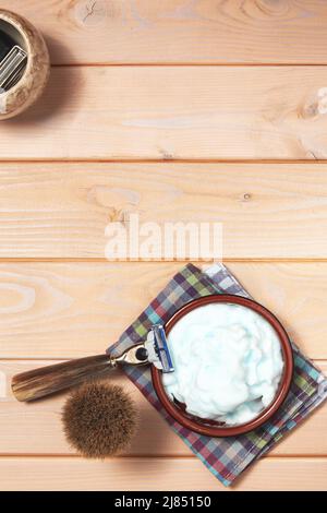 Shaving razor, brush, gel and electric trimmer on the wooden table. Vertical template with hygiene tools and copy space Stock Photo