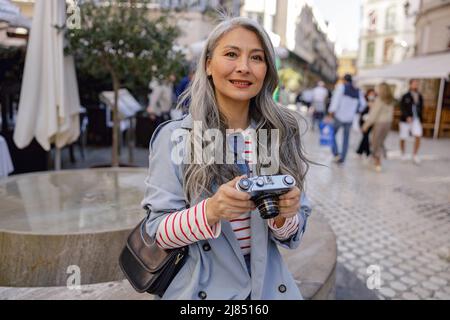 Cheerful female photographer strolling down city center Stock Photo