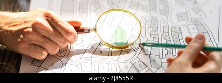 Close-up Of Human Hand Holding Magnifying Glass Over Paper Cadastre Map Stock Photo