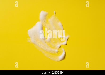 Foam texture of skin care cleanser. Swatches of soap, shampoo, and cleansing mousse foam with copy space on yellow background. Close-up of facial clea Stock Photo