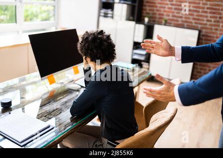 Close-up Of Businessperson Quarreling To Young Businesswoman At Desk Stock Photo