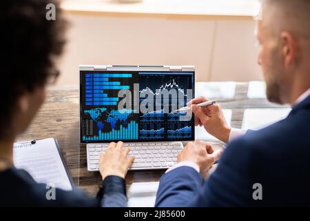 Two Businesspeople Analyzing Financial Graph On Laptop Stock Photo