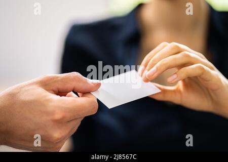 Close-up Of Two Businesspeople Hand Exchanging Visiting Card In Office Stock Photo