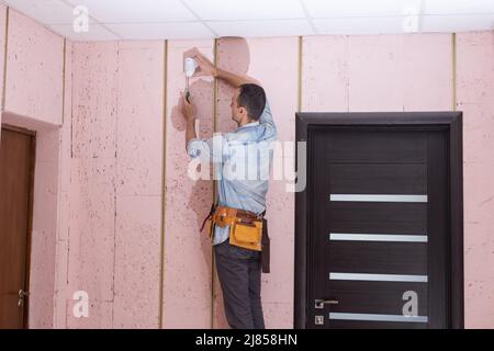 Young electrician installing security alarm on wall. Stock Photo