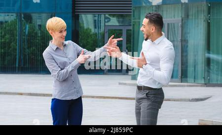 Multiracial couple business colleagues arabic spaniard man manager boss and caucasian adult blonde woman standing outdoors talking actively gesturing Stock Photo