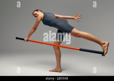 beautiful girl in sports uniform is training kung fu in the studio, fighter athlete, practicing martial arts with a stick Stock Photo