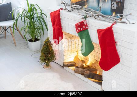 Fireplace with Christmas stockings in festive room interior. Stock Photo