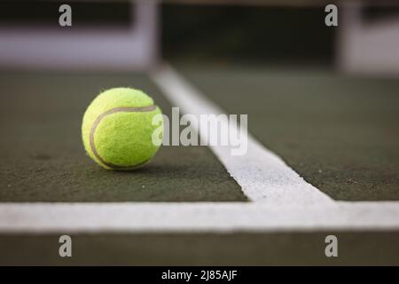 Close-up of yellow tennis ball by white lines on tennis court, copy space Stock Photo