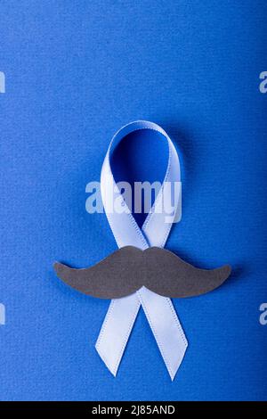 Close-up of of blue prostate cancer awareness ribbon with paper mustache on blue background Stock Photo