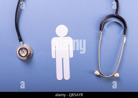 Directly above shot of stethoscope with paper man against blue background, copy space Stock Photo