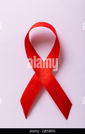 Overhead close-up of red aids awareness ribbon isolated against white background, copy space Stock Photo