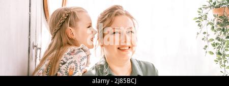 happy family mother with cute little kid daughter girl have fun together in suburb countryside home on sunny summer day. candid mom hugging and reads Stock Photo