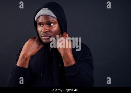 handsome afro-america male wearing gray hat and black hoody with hood serious and strong look at the camera studio shot background Stock Photo