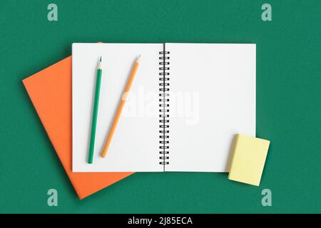 Notebook with pencil. Open notebook on dark green color background, office spiral notepad on table with blank pages. Top view. White Page for write. Stock Photo