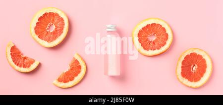 Vitamin c citrus lotion bottle with slices of grapefruit on pink background. SPA body treatment concept. Stock Photo