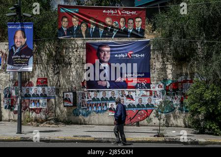 Beirut, Lebanon. 11th May, 2022. A man walks past different posters of parliament candidates in a street, ahead of the Parliamentary elections scheduled on the 15 of May. Credit: Marwan Naamani/dpa/Alamy Live News Stock Photo
