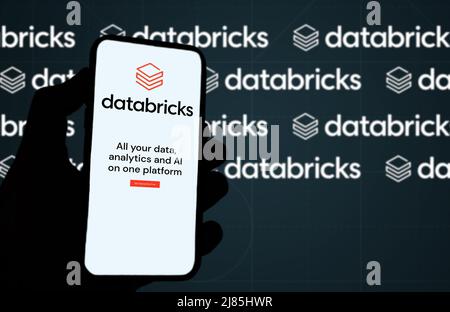 San Francisco, CA, US, May 2022: hand holding a phone with Databricks company web page on screen. In background the logo Databricks blurred and repeat Stock Photo