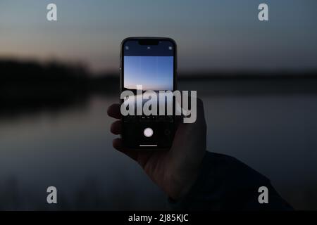 hand holding smart phone and taking photo of beautiful sunset Stock Photo
