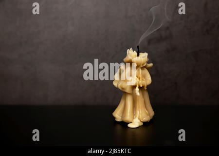 Wax candle, Yellow candle in the form of an extinguished angel extinguished, smoke from the oppression to the top. Stock Photo