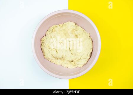 Kneaded pastry in plastic case, making bread concept, top view, isolated on white and yellow background, pastry for bread with copy space Stock Photo