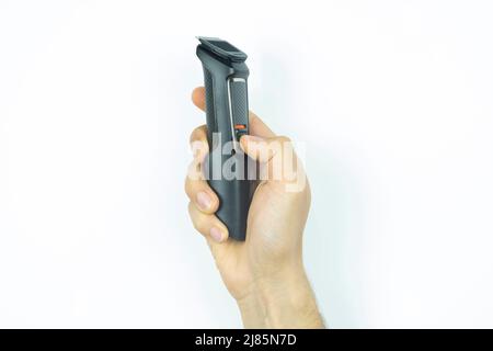 Man hand holding a black shaving machine, shave and barber idea, isolated on white background, front view of a wireless electric razor Stock Photo