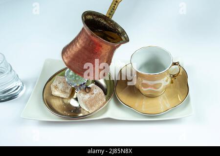 Pouring out Turkish coffee from traditional pot, isolated on white background, service of Turkish coffeee with delight and water, serving concep Stock Photo
