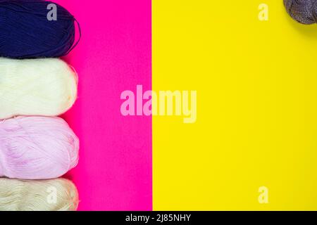 Colorful knitting thread isolated on pink and yellow background, colored background with copy space, handmade, hand knitting, top view, blue white Stock Photo