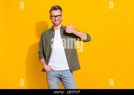 Portrait of attractive cheerful lucky successful guy showing thumbup isolated over bright yellow color background Stock Photo
