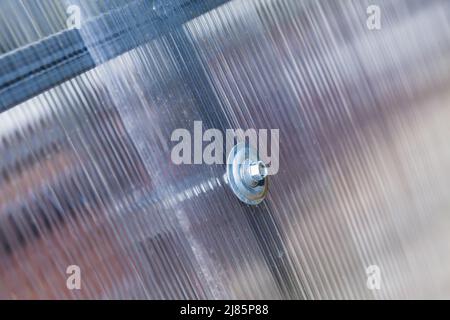 Modern greenhouse details. Connection of polycarbonate roof with steel frame, bolt with negative thermal expansion washer Stock Photo