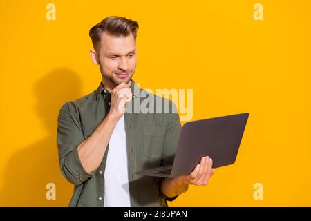 Portrait of attractive minded smart guy using laptop deciding order eshop booking isolated over bright yellow color background Stock Photo
