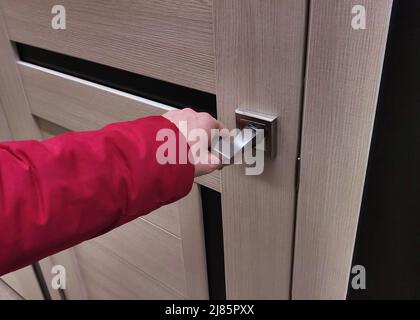 woman opens or closes door with her hand on handle Stock Photo