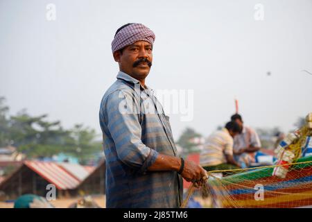 Portrait of fisherman standing in boat holding fishing net, Tangassery, Kerala, India. Stock Photo