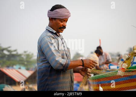 Portrait of fisherman standing in boat holding fishing net, Tangassery, Kerala, India. Stock Photo
