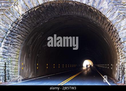 Two people walk through a tunnel, down a closed section of the Blue Ridge Parkway, outside of Asheville, NC, USA Stock Photo