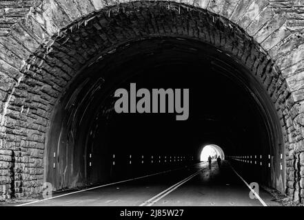 Two people walk through a tunnel, down a closed section of the Blue Ridge Parkway, outside of Asheville, NC, USA Stock Photo