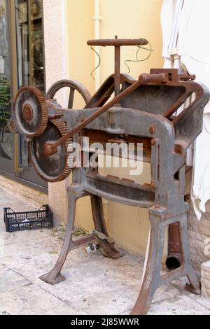 An antique bookbinding machine displayed on a street in Italy Stock Photo