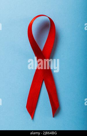 Overhead close-up of red aids awareness ribbon isolated against blue background, copy space Stock Photo