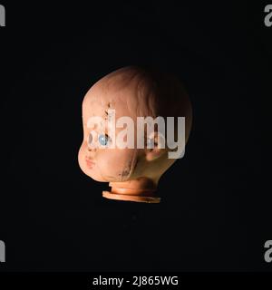 Damaged Dirty Doll head on black background Stock Photo