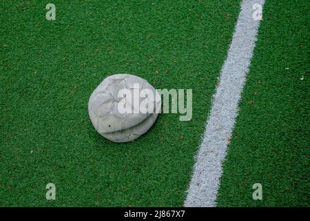 deflated soccer ball on green grass sport field. Impossible to play. Stock Photo