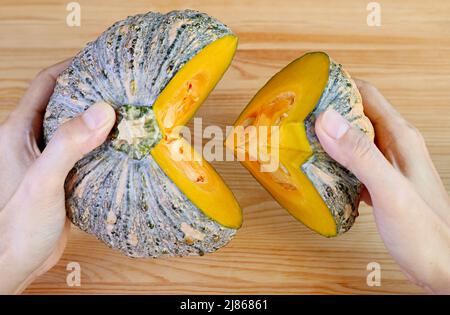 Hand Holding a Cut Fresh Squash or Thai Pumpkin on Light Brown Wooden Background Stock Photo