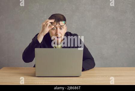Scared man having problem with laptop and looking at screen with shocked face expression Stock Photo