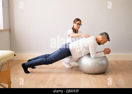 Physical Physiotherapy And Rehabilitation. Professional Therapist Exercising With Patient Stock Photo