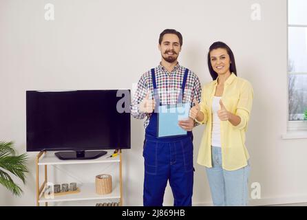 Happy customer and repairman showing thumbs up after the worker has repaired a TV set Stock Photo
