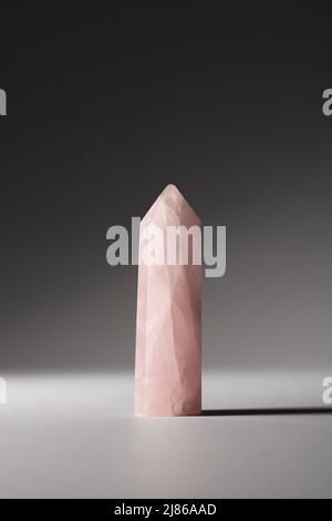 One rose quartz crystal on gray background. Healing minerals, gemstones for relaxation Stock Photo