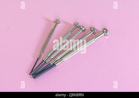 Different mini for delicate work on smallest screws in electronics and on light pink background Stock Photo